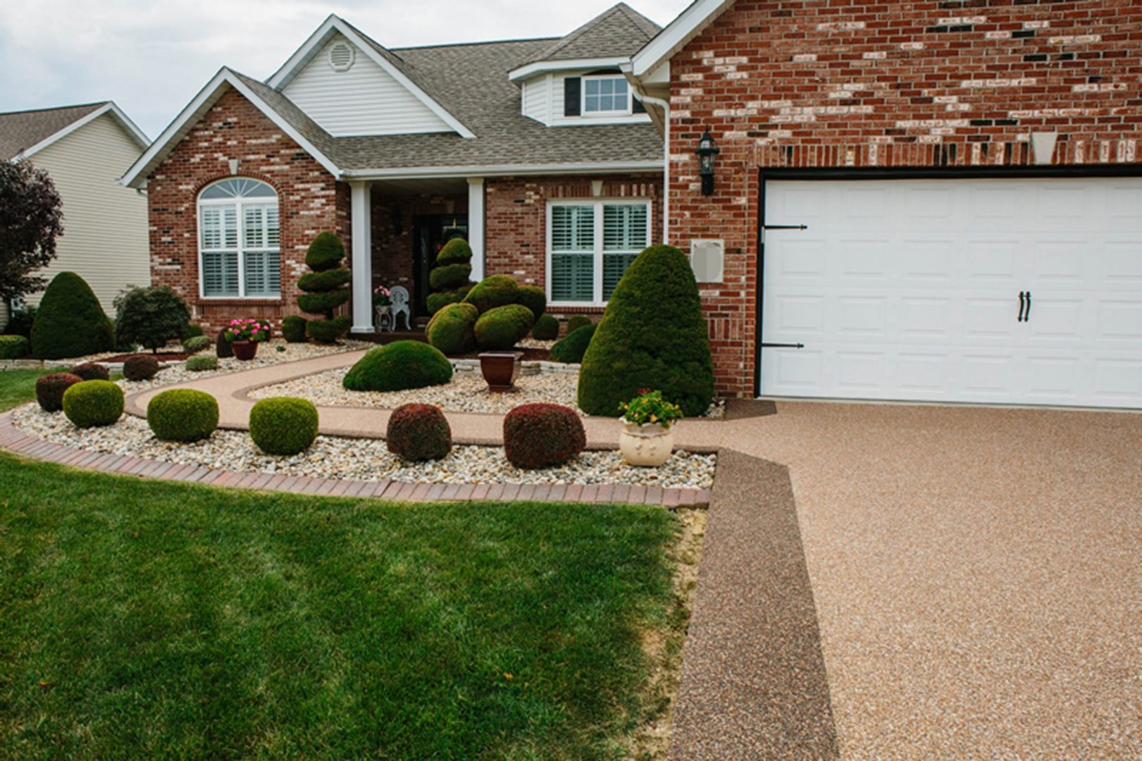 Real Stone Bond resin-bound stone driveway and walkway at a brick home, fine tan aggregate with dark brown border