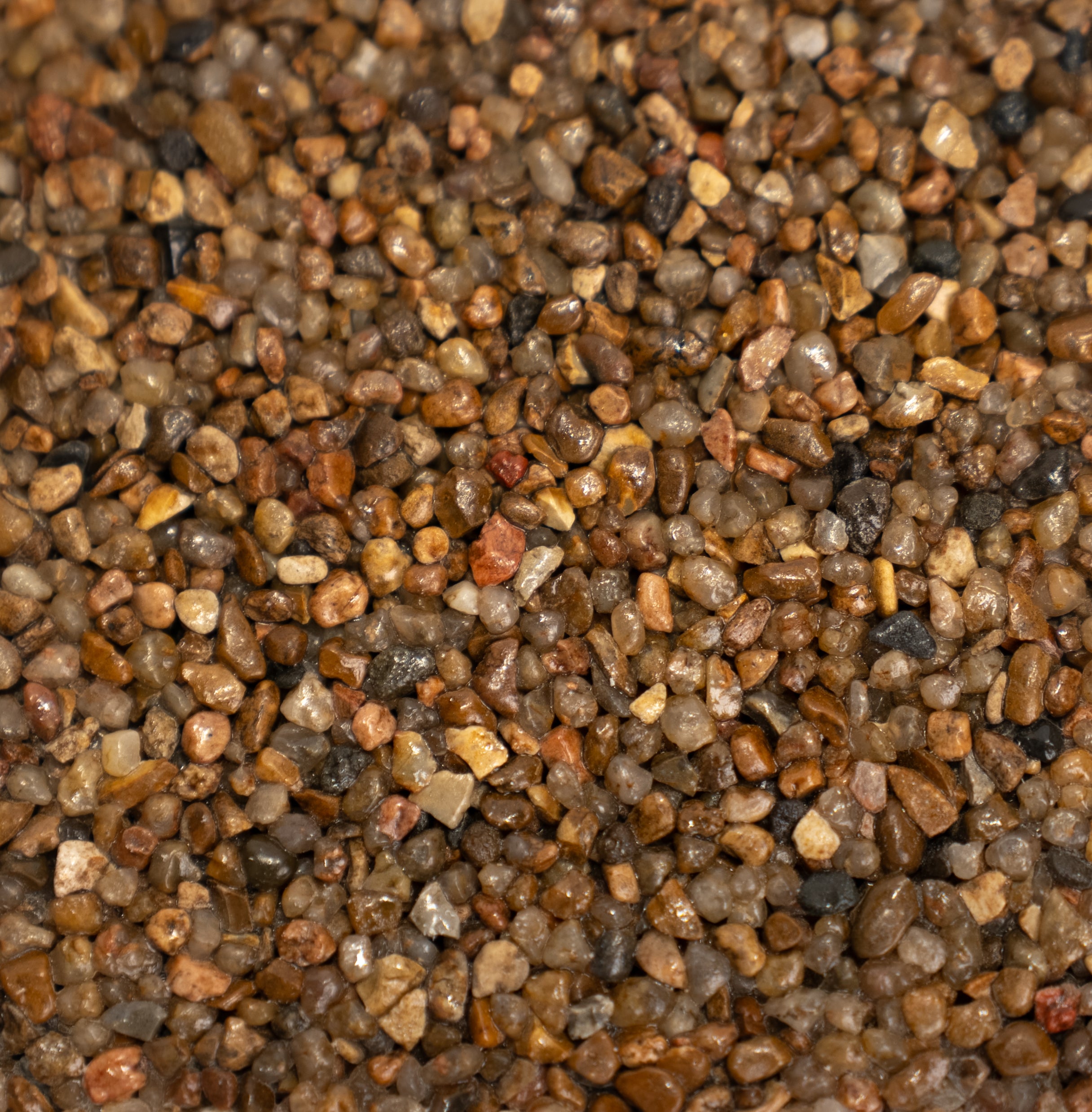Close-up of multicolored gravel with various shades of brown, dark gray, and black.