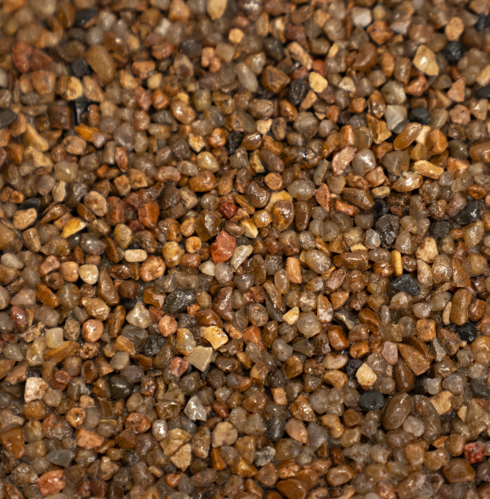 Close-up of multicolored gravel with various shades of brown, dark gray, and black.
