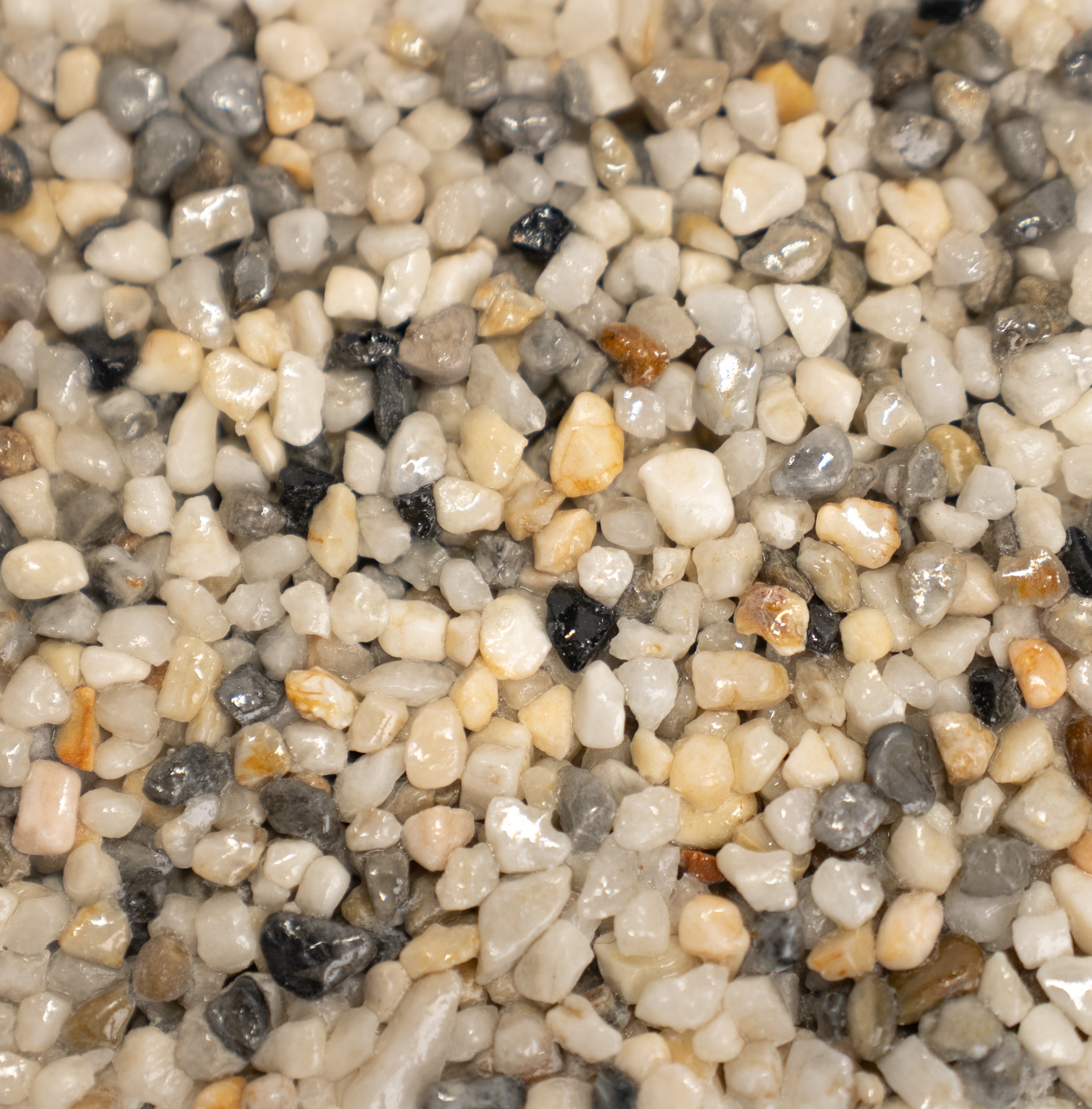 Close-up of small pearl pebbles with various colors including white, gray, and  pops of orange.